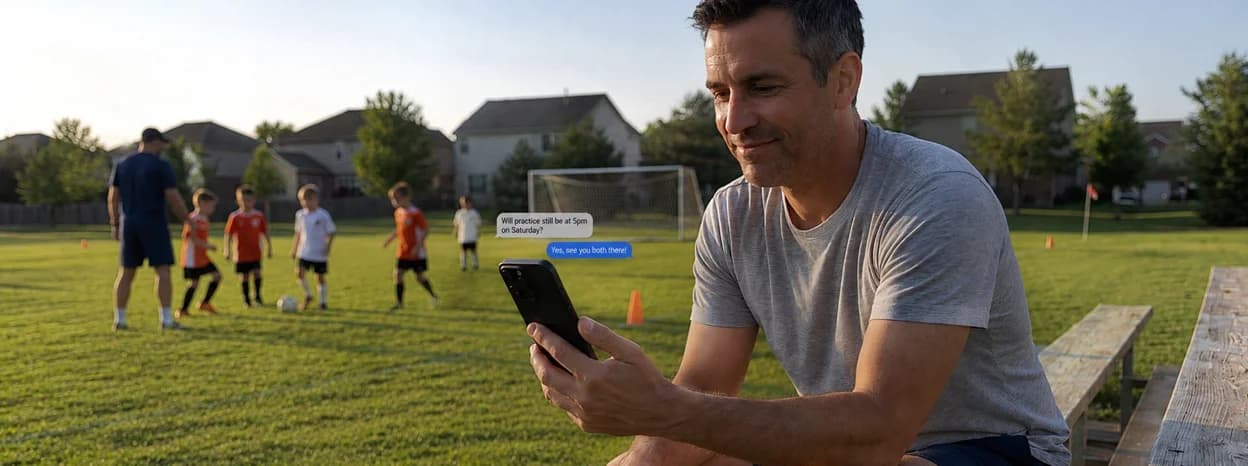 Coach messaging on a phone beside a youth soccer practice