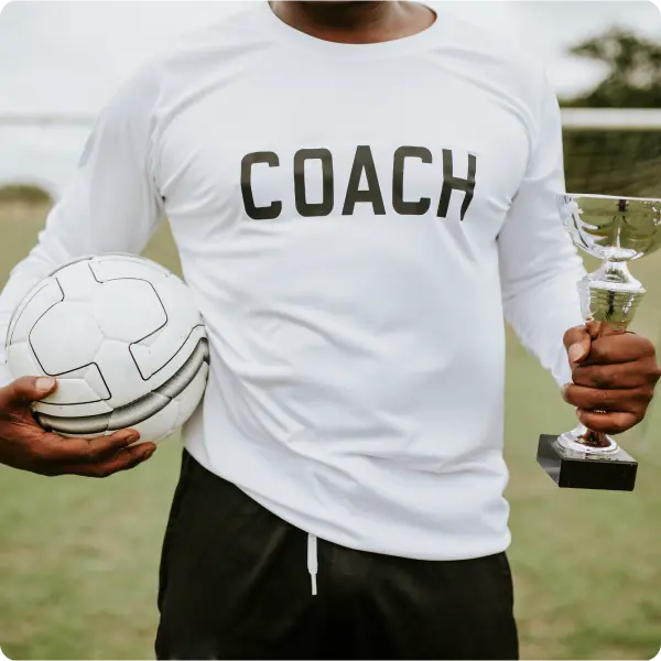 Coach holding trophy and soccer ball